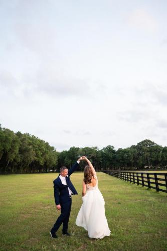 groom twirling bride in field