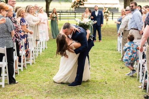groom kissing bride in outdoor wedding ceremony aisle
